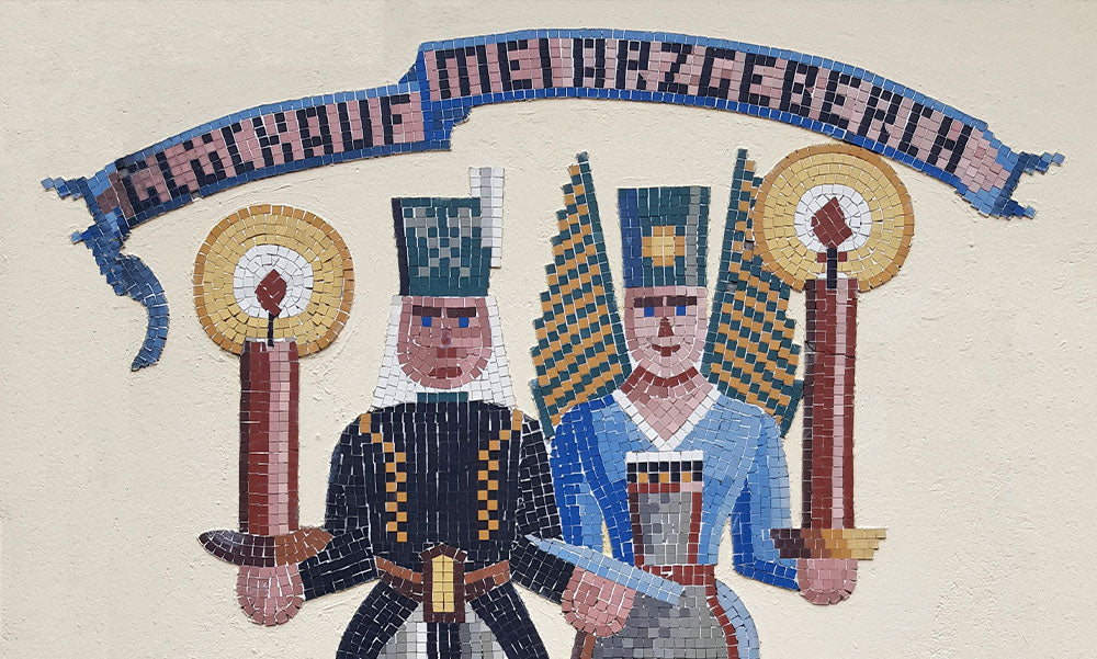 Farbiges Mosaik zweier Bergleute mit Kerzen unter dem Schriftzug „Glückauf im Erzgebirge“