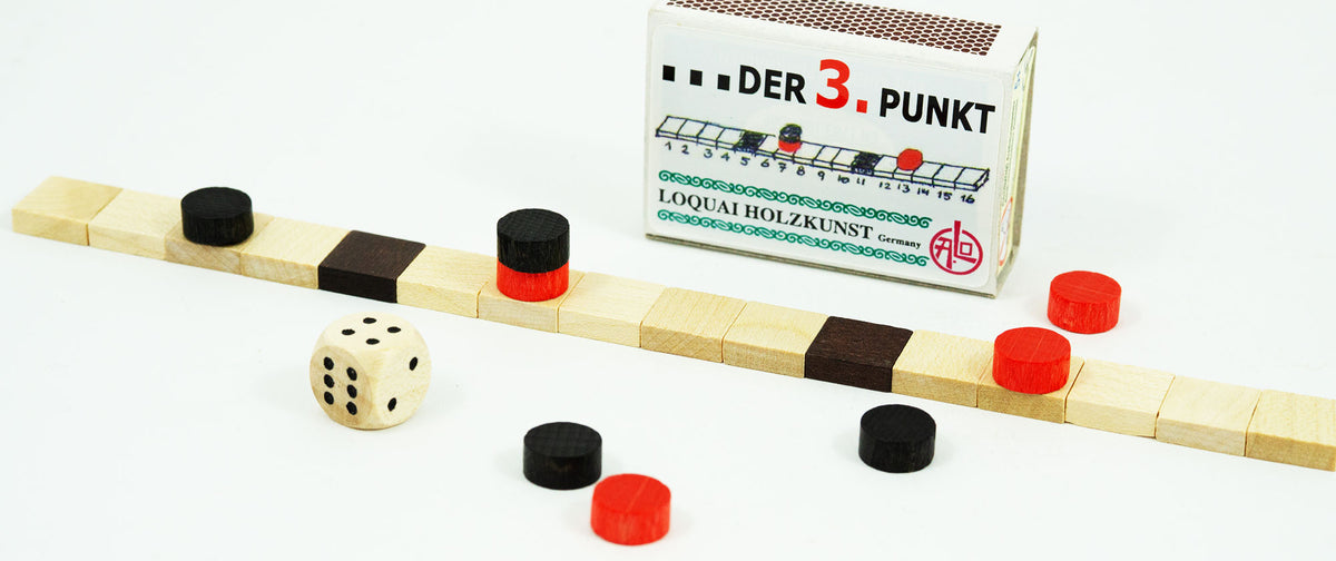 Holzspiel „Der 3. Punkt“ mit Würfel und Spielsteinen vor der Streichholzschachtel